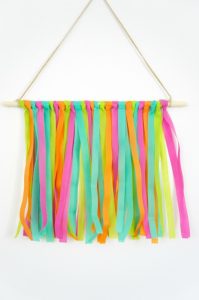 Create your own colorful, on-trend wall hanging using strips of Oly*Fun. This simple project is quick and easy to make, and is a fun way to freshen up your decor for summer. It even becomes a unique way to display photos and mementos, making it a great DIY for dorm rooms!